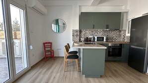 Una cocina moderna con una isla central, un comedor con una silla roja y un amplio ventanal que proporciona luz natural.
