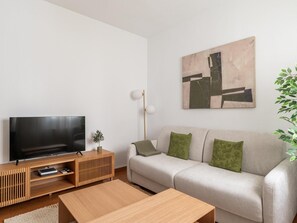 Ein modernes Wohnzimmer mit Flachbildfernseher, Holzkonsole, Sofa und einem Gemälde an der Wand.