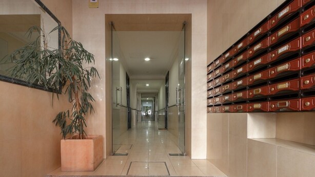 A hallway with a potted plant, a staircase, and a row of filing cabinets. - Ibiza - Parque del Retiro- 2 Bedrooms (Madrid)