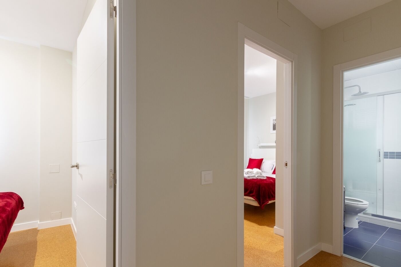 Una habitación de hotel con cama, un baño con ducha y un pasillo que conduce a otra habitación.