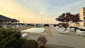 A pool area with lounge chairs and a small pool, surrounded by buildings and a clear sky. - ⨳ Lake Erie Waterfront condo conveniently located near Jet Express - 1BR 1 BA ⨳ (Port Clinton)