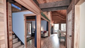 Interior de madera con una escalera que lleva a una habitación con vistas, un cartel que dice "MAGIC MILE", y un pasillo con una puerta y una silla.
