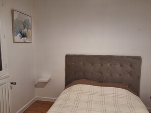 Cozy retreat with a single bed featuring a tufted headboard, a simple nightstand, and a framed artwork.
