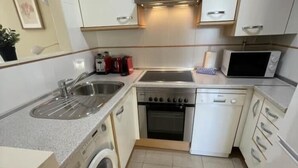 Een kleine keuken met een spoelbak, kookplaat, oven, magnetron en een wasmachine.