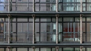 A multi-story building with large windows and a balcony with metal railings.