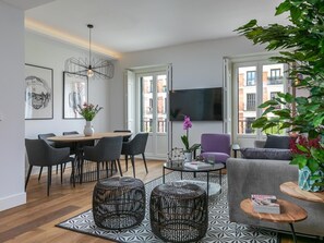A modern living room with a dining area, a flat-screen TV, and large windows. - Alcalá - Parque del Retiro - 2 Bedrooms (Madrid)