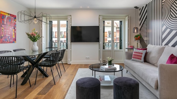 Una sala de estar moderna con comedor, sofá, mesa de centro y televisor.