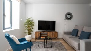 A living room with a TV, sofa, blue chair, and a floor lamp.
