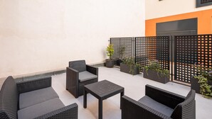 Un área de estar al aire libre con mobiliario de mimbre y plantas en macetas.