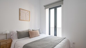 Un dormitorio con cama, mesita de noche, lámpara y ventana con vistas.