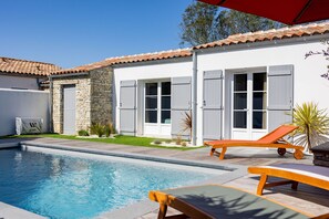 A swimming pool with lounge chairs and a covered patio area. - La Dionysienne piscine privée (Saint-Denis-d´Oléron)