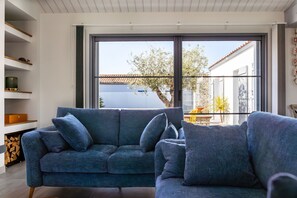 A modern living room with a blue sofa, a fireplace, and a large window offering a view of the outdoors.