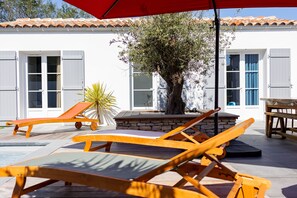 A poolside area with wooden lounge chairs and a red umbrella. - La Dionysienne piscine privée (Saint-Denis-d´Oléron)