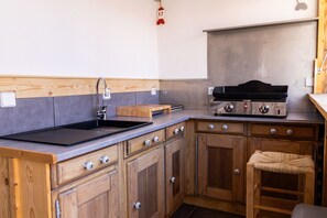 Een compacte keuken met houten kastjes, een zwarte gootsteen en een gasfornuis.