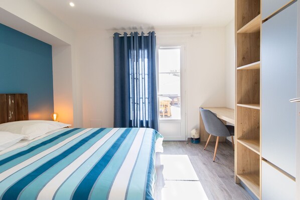 A bedroom with a bed, a desk, and a wardrobe.