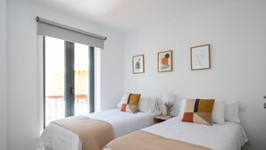 A hotel room with two beds, a large window, and a balcony.