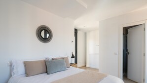 A bedroom with a large bed, a round mirror, and a door leading to another room.