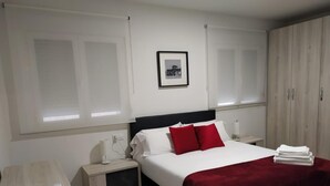 Ein Schlafzimmer mit Bett, Nachttischen, Schreibtisch und Kleiderschrank.