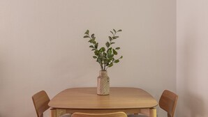 A dining table with four chairs, a vase with green leaves, and a plain wall. - Las Tablas - 1 Bedroom with sofa bed and terrace (Madrid)