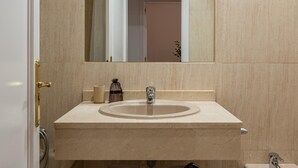 A bathroom with a beige marble sink, a mirror above it, and a door leading to another room. - Las Tablas - 1 Bedroom with sofa bed and terrace (Madrid)