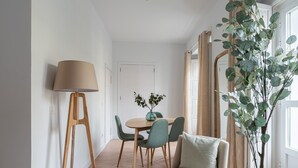 Un comedor moderno con una mesa redonda, dos sillas, una lámpara de pie y una planta grande.