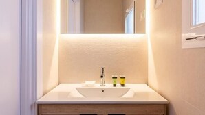 A bathroom with a white sink, wooden cabinet, and a mirror above the sink. - Tirso de Molina - 1 Bedroom (Madrid)