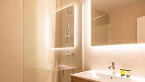 A modern bathroom with a glass shower enclosure, a wooden vanity with a sink, and a mirror above the vanity.