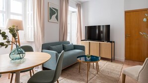 A modern living room with a sofa, a TV, a dining table, and a small side table.