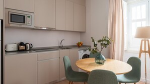 A modern kitchen with a microwave, toaster, and sink. There is a dining area with a table and chairs, and a vase with a plant.