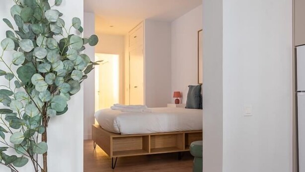 A bedroom with a wooden bed, a green chair, and a plant.