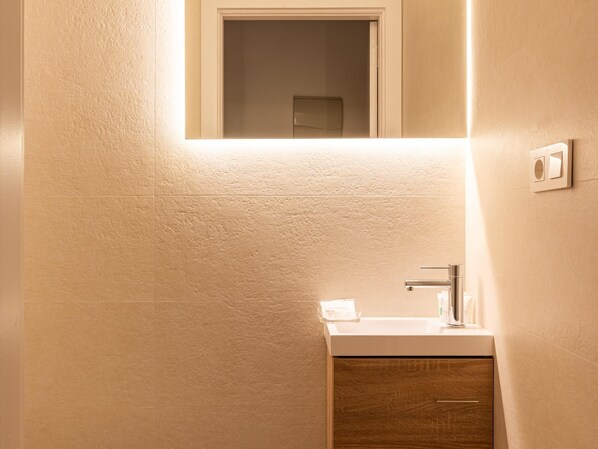 A bathroom with a white sink, a mirror above it, and a wooden cabinet below.