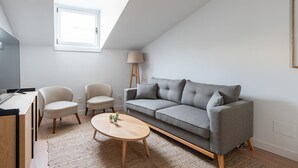 Un loft moderno con un sofá gris, dos sillones, una mesa de centro de madera y una lámpara de pie.