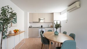 Cocina moderna con comedor, que incluye lavadora, microondas y una mesa con sillas.