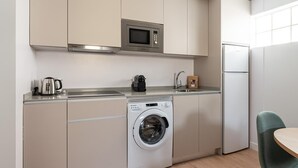 Una cocina compacta con lavadora, microondas y refrigerador.