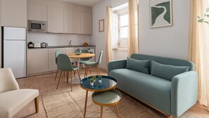 Un espace de vie compact comprenant un coin cuisine, un canapé, une table à manger avec des chaises et une petite table basse.