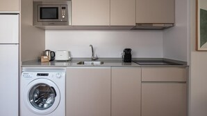 Eine kompakte Küche mit Mikrowelle, Toaster, Kaffeemaschine und Waschmaschine.