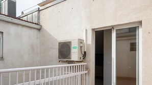 Ein Gebäude mit weißem Balkonlaufgeländer, einer Schiebetür aus Glas und einer Wandklimaanlage.