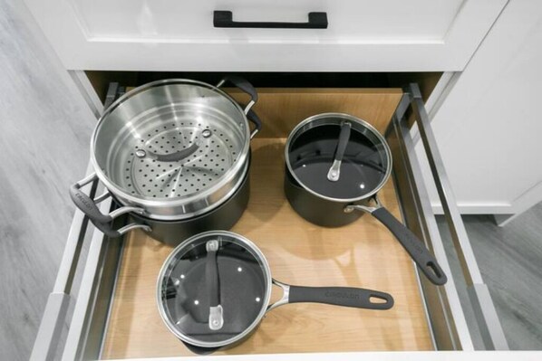 Eine Küchenschublade mit drei Töpfen und Pfannen.
