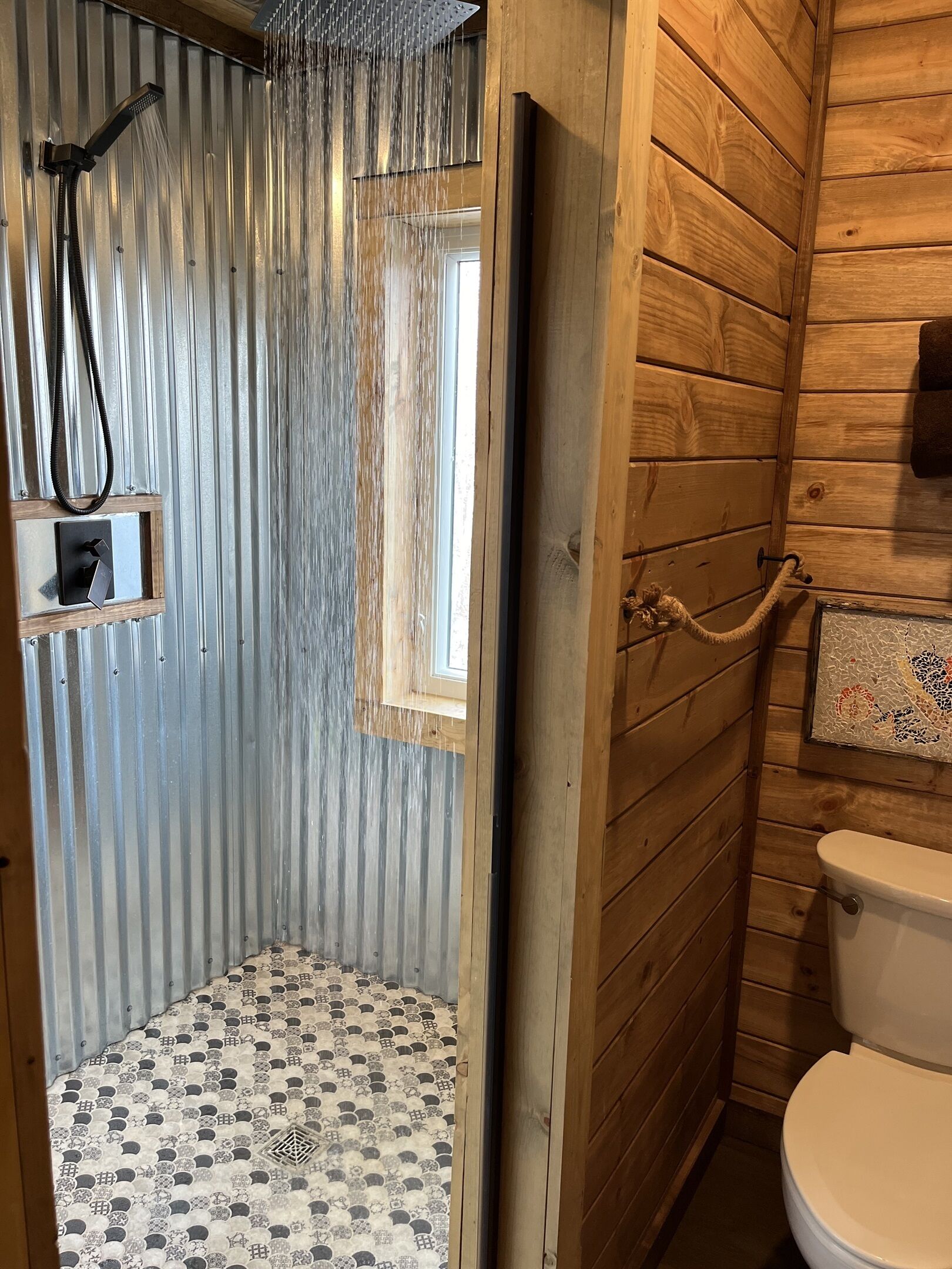 Ein Badezimmer einer Holzhütte mit Dusche, Toilette und Fenster.
