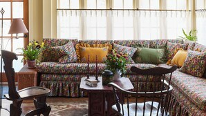 A cozy living room with a patterned sofa, a wooden chair, a small table with books and a vase, and a ceiling mural. - Six Bells Countryside Inn (Rosendale)