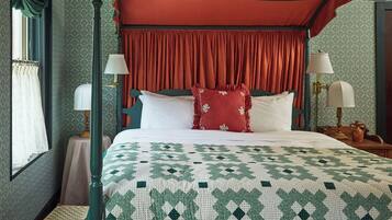 Un lit à baldaquin avec un ciel de lit vert, des rideaux rouges et une courtepointe à motifs.