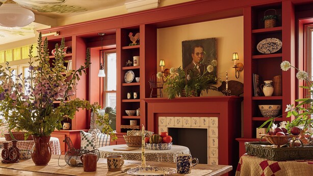 A traditional dining room with a wooden table set for a meal, surrounded by red walls and a fireplace. - Six Bells Countryside Inn (Rosendale)