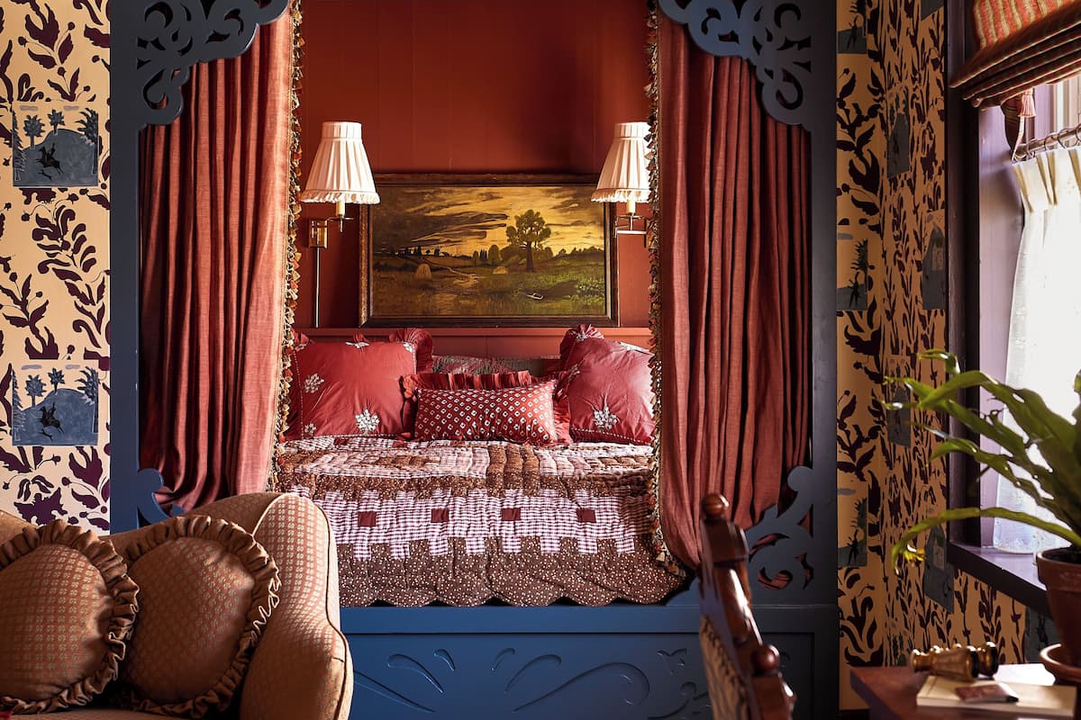 A cozy bedroom with a bed, a chair, and a window with curtains.