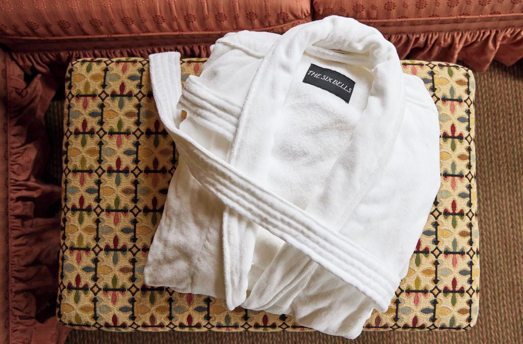 Una bata blanca con una etiqueta sobre un cojín estampado en un sofá.