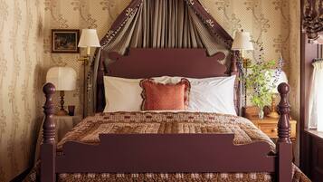 A traditional four-poster bed with a dark wooden frame, a quilted bedspread, and a matching bench.