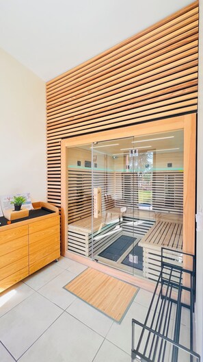Une chambre moderne avec un plafond à lattes de bois, une porte vitrée donnant sur un balcon et un meuble en bois orné d’une plante.