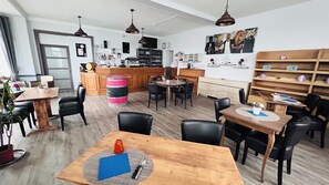 A modern kitchen with wooden cabinets, a central island, and a dining area with tables and chairs. - Group gîte, jacuzzi-sauna-heated pool 43prs (Vivoin)