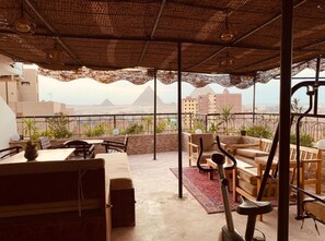 An outdoor patio with seating, a table, and a view of the pyramids. - Draz Pyramids View (Giza)