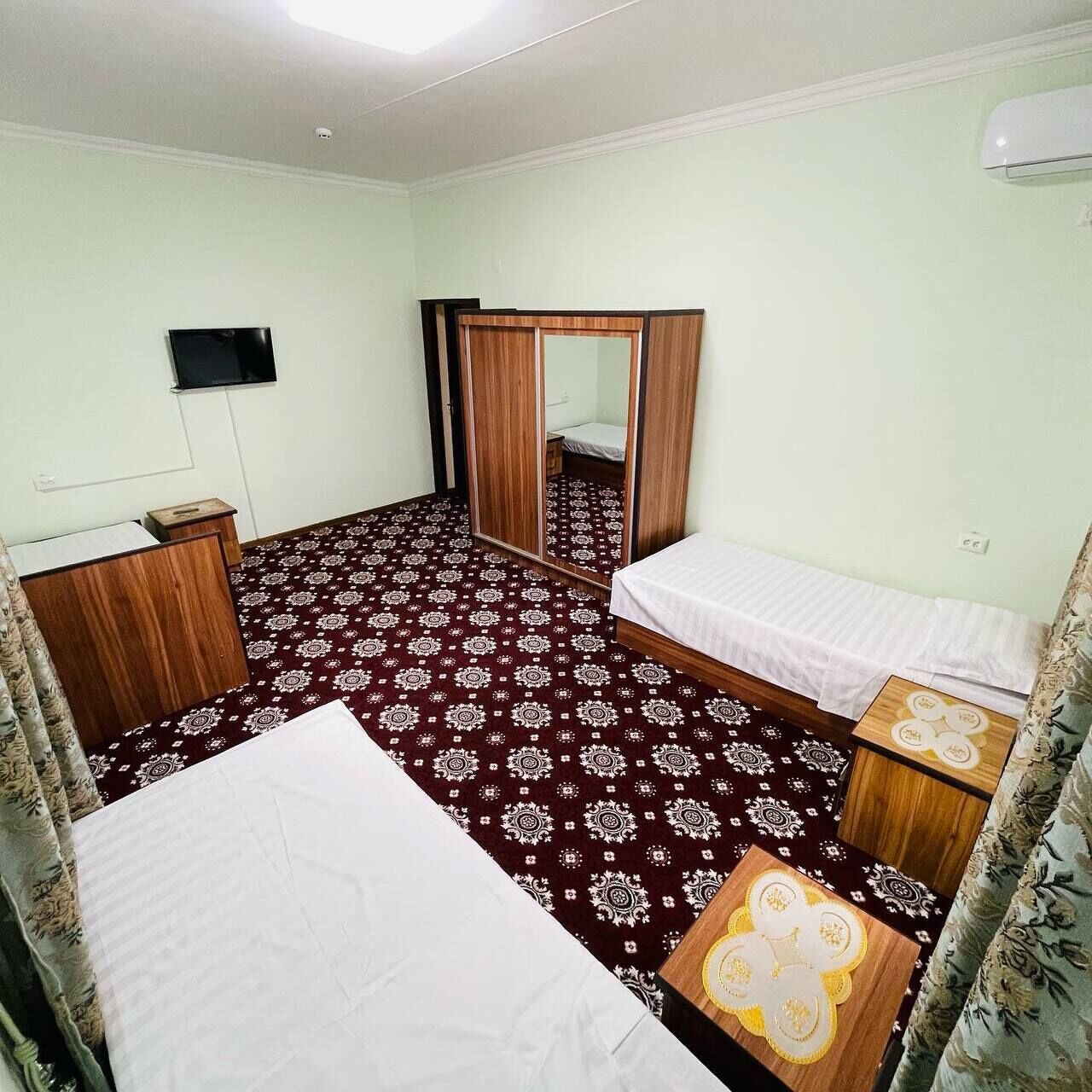Une chambre d’hôtel comprenant un lit, une table de chevet, un miroir, une armoire et un téléviseur.