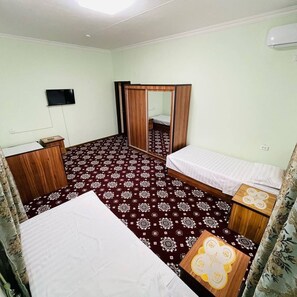 Una habitación de hotel con cama, mesita de noche, espejo, armario y televisión.